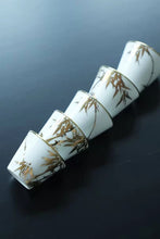 Load image into Gallery viewer, Tongxin She Teahouse Selection | Creamy White Gilded Bamboo Teacups Snow-white porcelain adorned with bamboo painted in gilded pigment.
A gilded rim encircles the cup, freezing tranquil time upon the vessel.