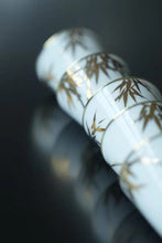 Load image into Gallery viewer, Tongxin She Teahouse Selection | Creamy White Gilded Bamboo Teacups Snow-white porcelain adorned with bamboo painted in gilded pigment.
A gilded rim encircles the cup, freezing tranquil time upon the vessel.
